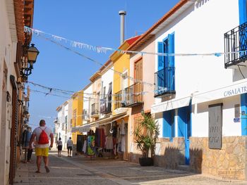 Rear view of man walking amidst buildings in city