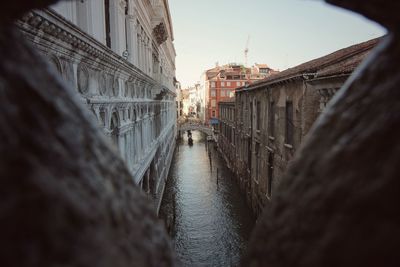 Canal amidst residential buildings seen through hole