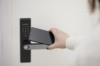 Woman unlocking smart door of house with mobile phone