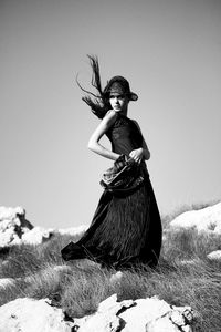 Portrait of young woman standing on field against clear sky during winter