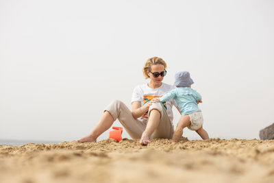 Portrait of woman sitting on sand at beach