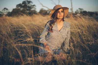 Young woman in hat standing on field