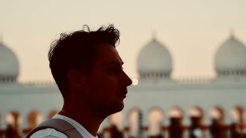 Portrait of man looking away against building