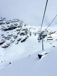 Ski lift over snowcapped mountains against sky