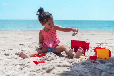 Rear view of woman sitting on sand at beach