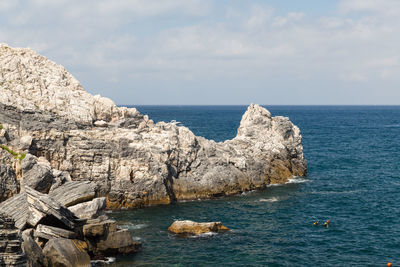 Rocks by sea against sky