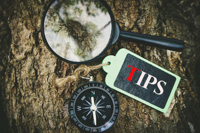 Tips  text written on tag with compass and magnifying glass on wooden background.