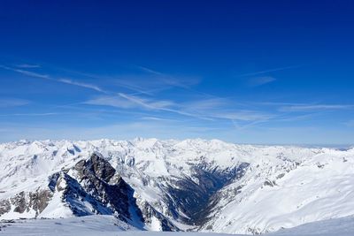 Scenic view of snowcapped mountains against blue sky