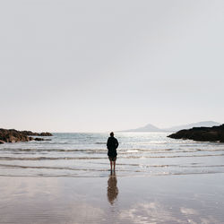 Rear view of silhouette man walking on beach