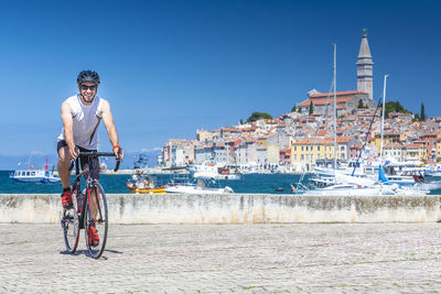 Man on bicycle by sea against sky