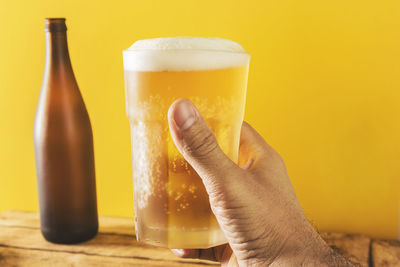 Close-up of hand holding glass of beer