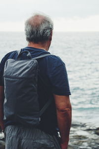 Rear view of man standing against sea