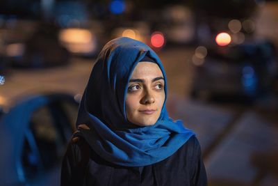 Young woman wearing hijab looking away at night