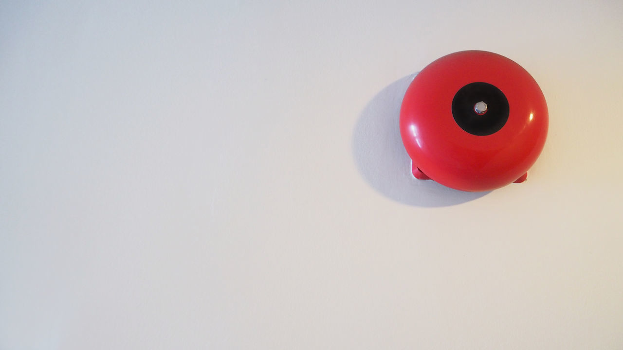 HIGH ANGLE VIEW OF RED TOY ON WHITE WALL