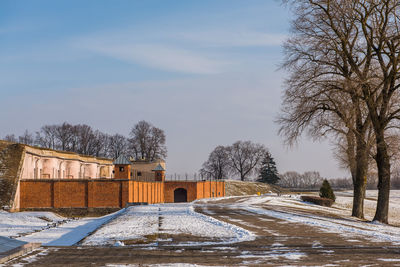 Snow covered houses by building against sky