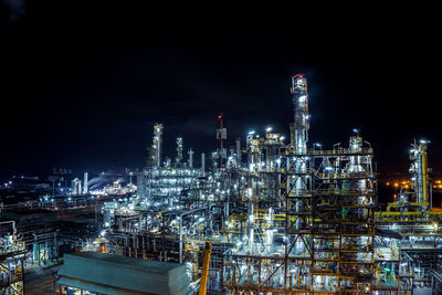 Illuminated factory against sky at night