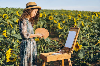 Full length of young woman using smart phone against sky