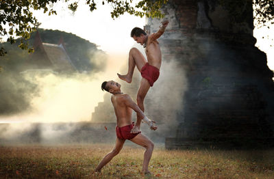 Full length of shirtless man standing against sky