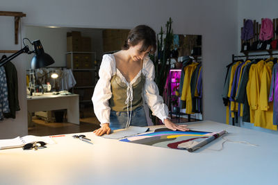 Young designer woman dressmaker work on new clothes collection in studio workshop. small business.