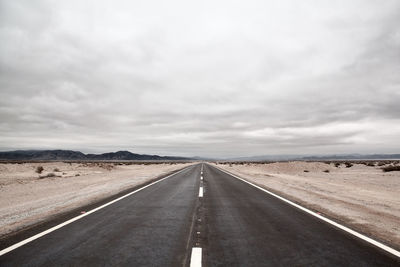 Empty road against cloudy sky