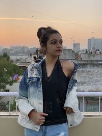 Portrait of young woman standing against cityscape