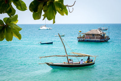 Fishing boats in sea against clear sky