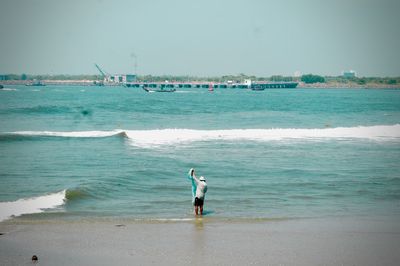 Rear view of man on beach against sky