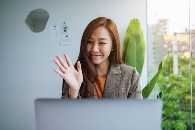 Young woman using laptop while sitting on chair at home