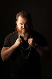 Portrait of man standing against black background