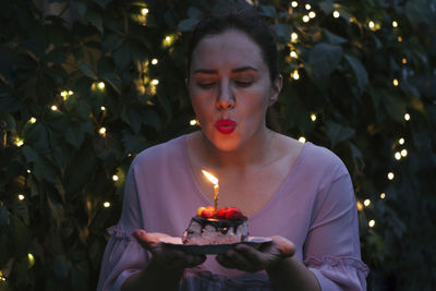 Woman blowing on piece of cake with birthday candle