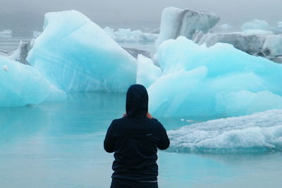 Rear view of man standing in frozen lake