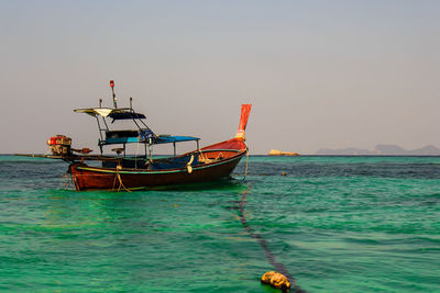 Fishing boat moored in sea against clear sky