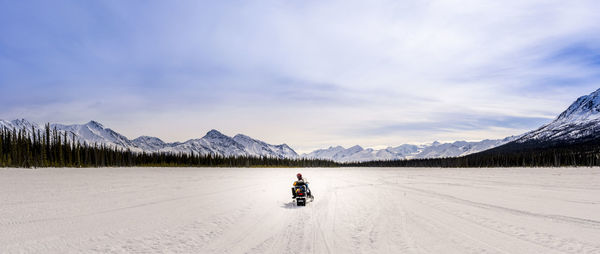 Rear view of man riding motorcycle on road against sky