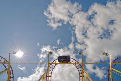 Low angle view of ferris wheel against cloudy sky