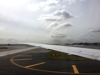 Airplane on runway against cloudy sky