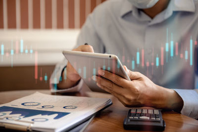 Midsection of man using mobile phone on table