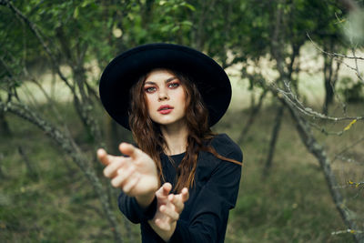 Portrait of young woman standing against tree