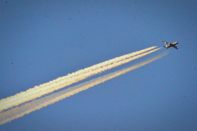 Low angle view of airplane flying against clear blue sky