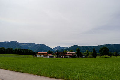 Houses on field by mountains against sky