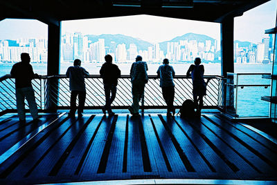 People standing on railing in city against sky