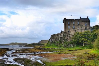 Buildings at waterfront against cloudy sky