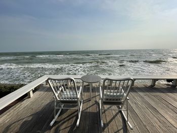 Deck chairs on beach against sky