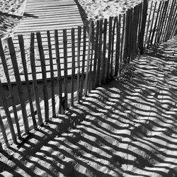 Shadow of wooden fence on field