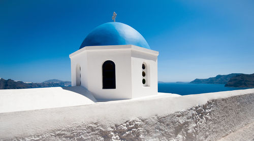 Building by sea against blue sky