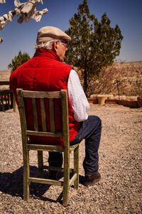 Rear view of senior man looking away while sitting on chair outdoors