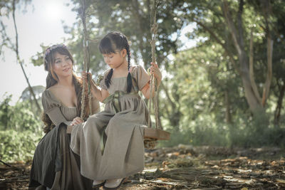 Mother looking at daughter sitting on swing