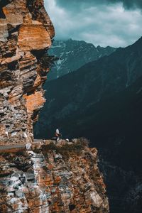 Hiker standing on cliff against mountains