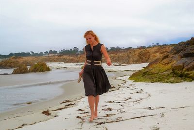 Full length portrait of young woman walking on beach