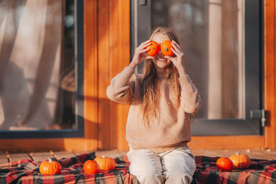 Young woman wearing mask standing against orange wall