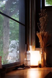 Illuminated lamp on table by window at home